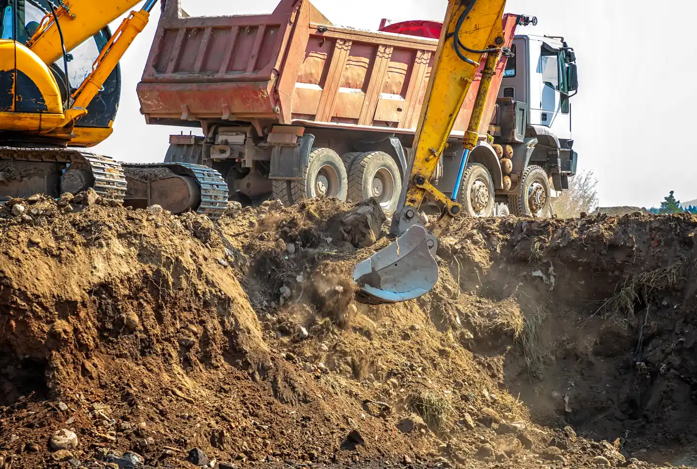 Bager nakladá výkopovú zeminu pri nákladnom vozidle